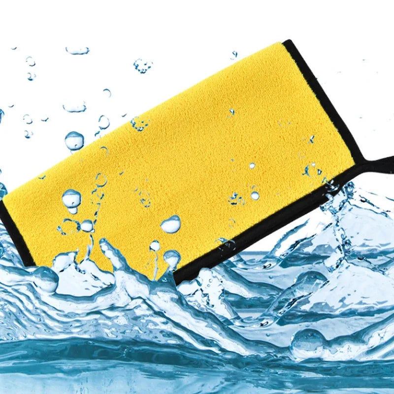 Yellow microfiber car cleaning towel being used to wipe away water droplets from a surface.