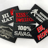 A collection of black embroidered iron-on patches featuring humorous text like HI HAT and Savage