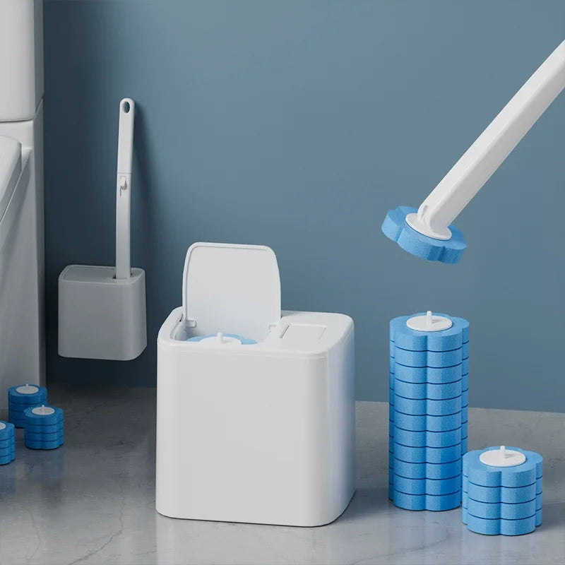A white disposable toilet cleaning brush kit with an auto-open lid and blue cleaning discs displayed against a gray wall.