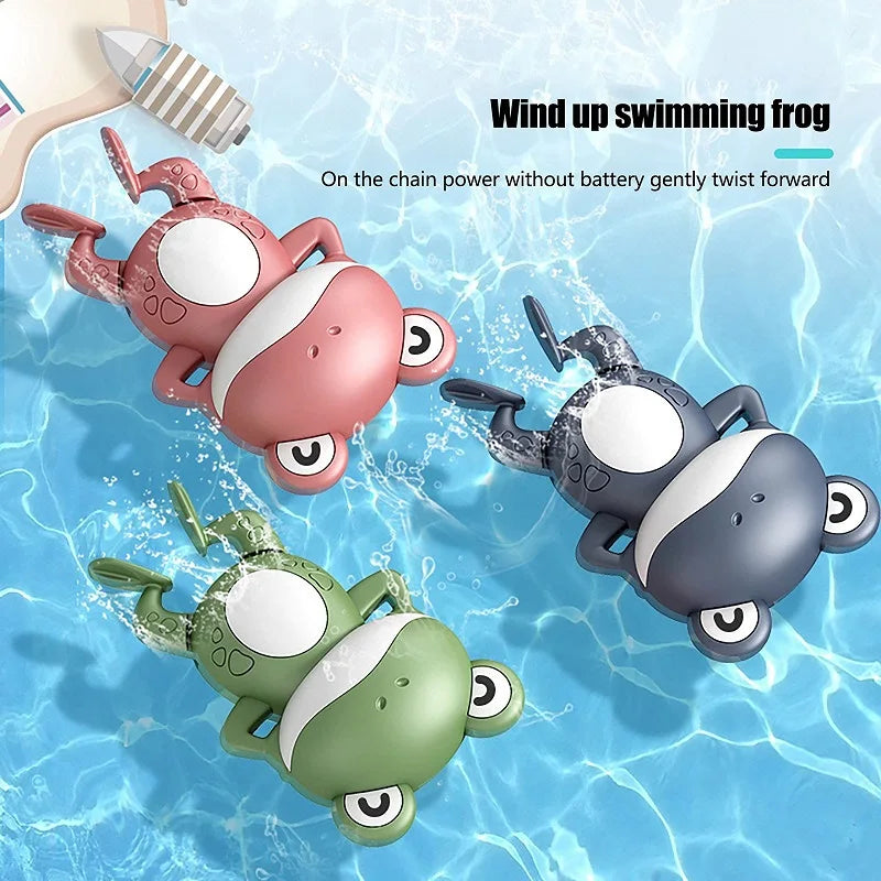 A set of wind up swimming frog toys in pink, gray, and green floating in water.