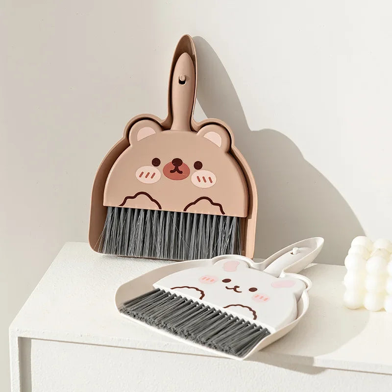 A set of pink cartoon-themed broom and dustpan for tabletop cleaning