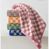 A stack of soft plaid cotton bath towels in various colors including purple, orange, green, and blue.