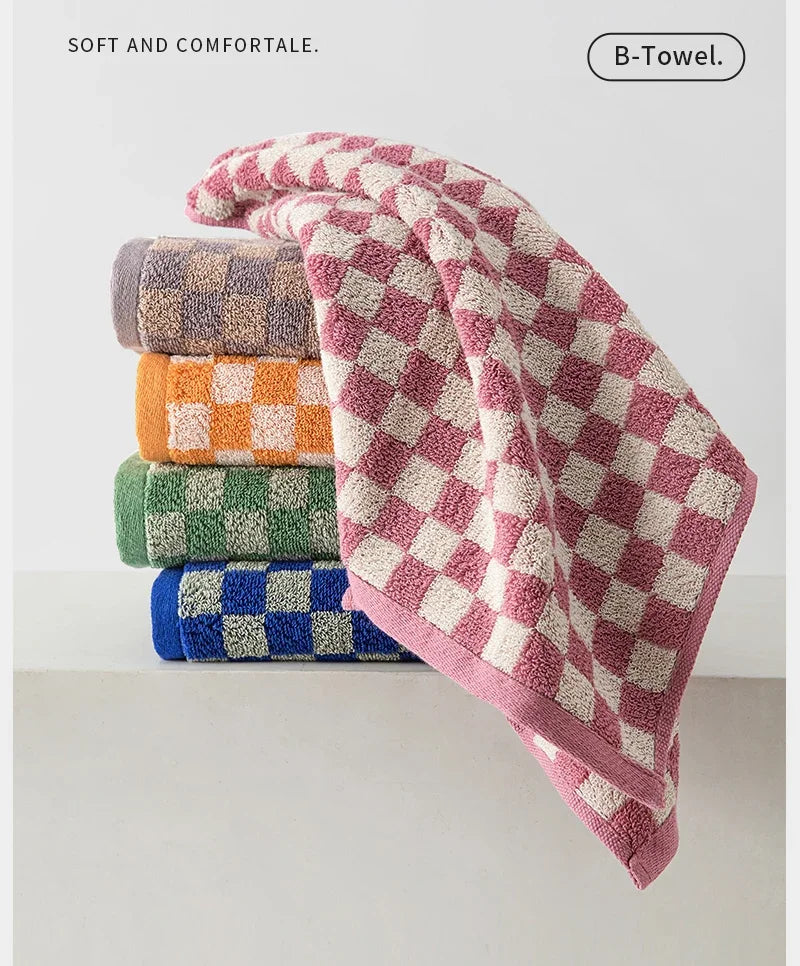 A stack of soft plaid cotton bath towels in various colors including purple, orange, green, and blue.