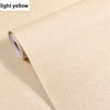 Roll of light yellow embossed silk self-adhesive wallpaper being peeled from its roll.