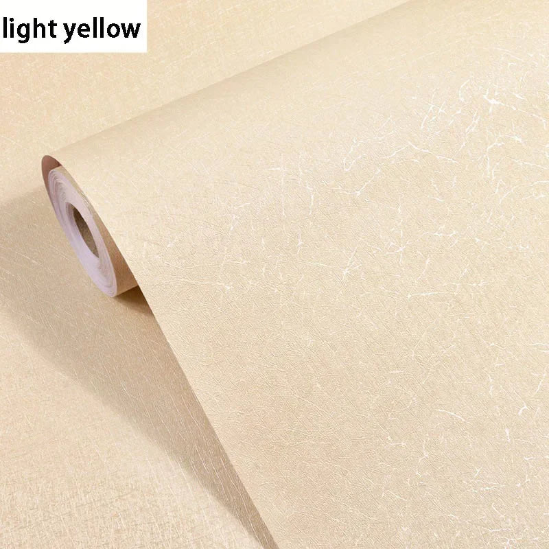 Roll of light yellow embossed silk self-adhesive wallpaper being peeled from its roll.