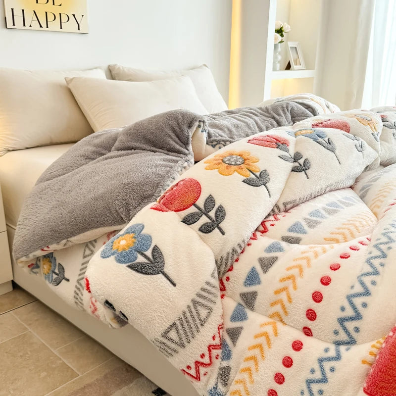 A close-up of a beige and gray plush throw blanket with floral and geometric patterns draped over a white sofa.