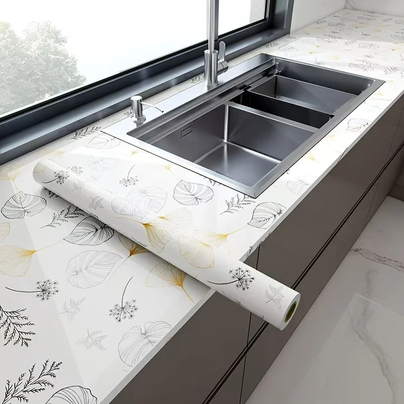 A stainless steel kitchen sink installed in a modern cabinet with white marble peel-and-stick wallpaper.