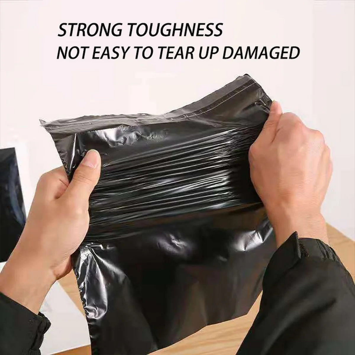 Hands are sealing a black self-seal poly mailer bag, demonstrating its strong toughness and resistance to tearing.