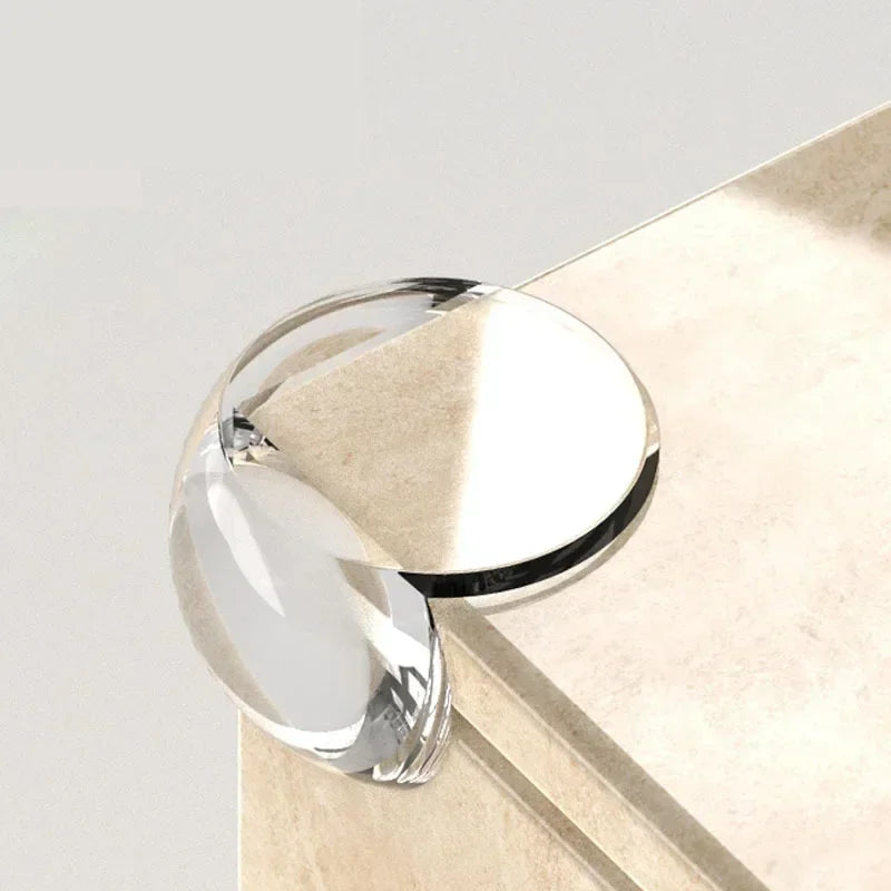 Clear silicone corner edge guards for baby safety resting on a light beige surface.