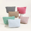 A collection of plaid fabric makeup bags in black, pink, brown, green, and purple arranged on a white surface.