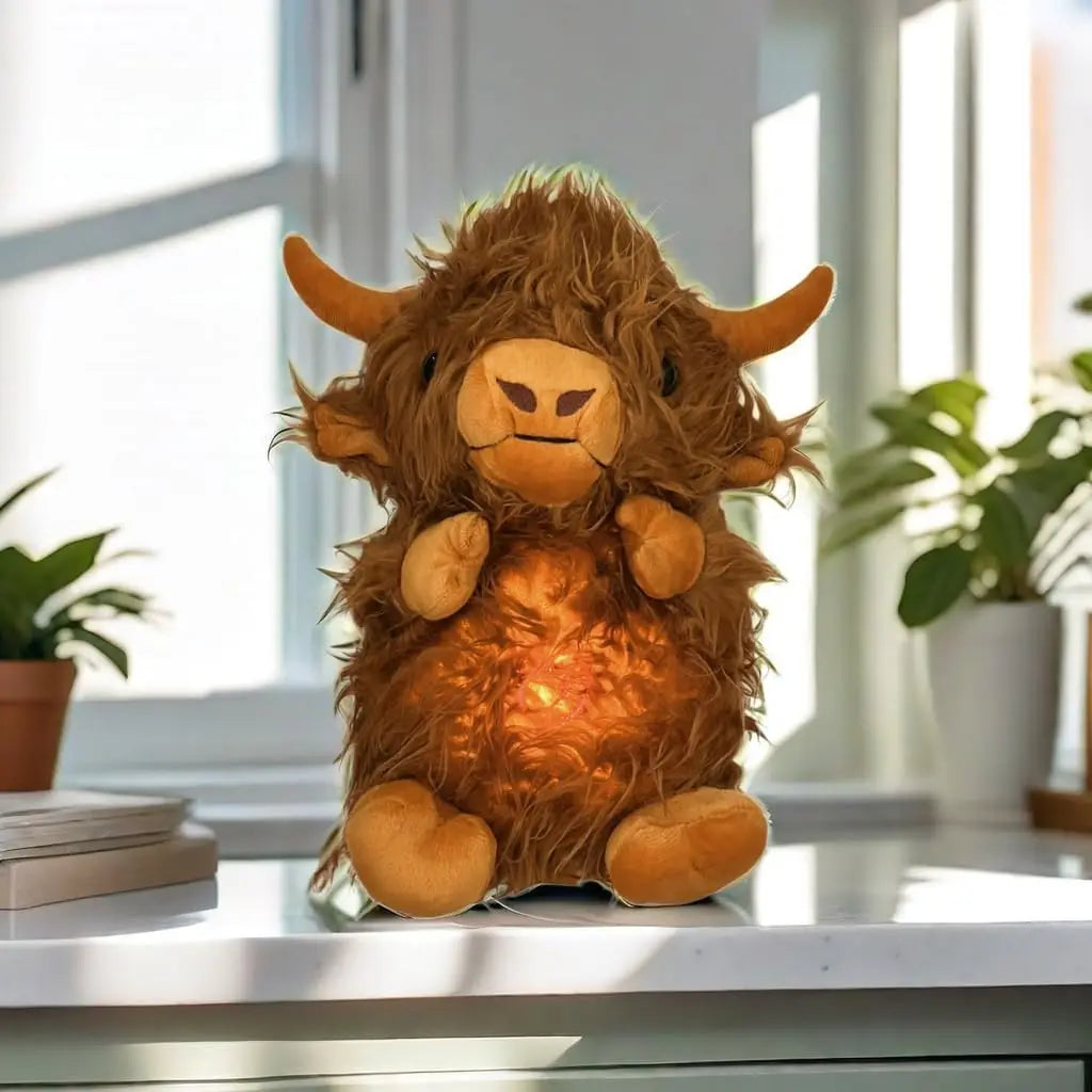 A fluffy brown Highland cow plush toy with breathing motion and light sitting on a white surface.
