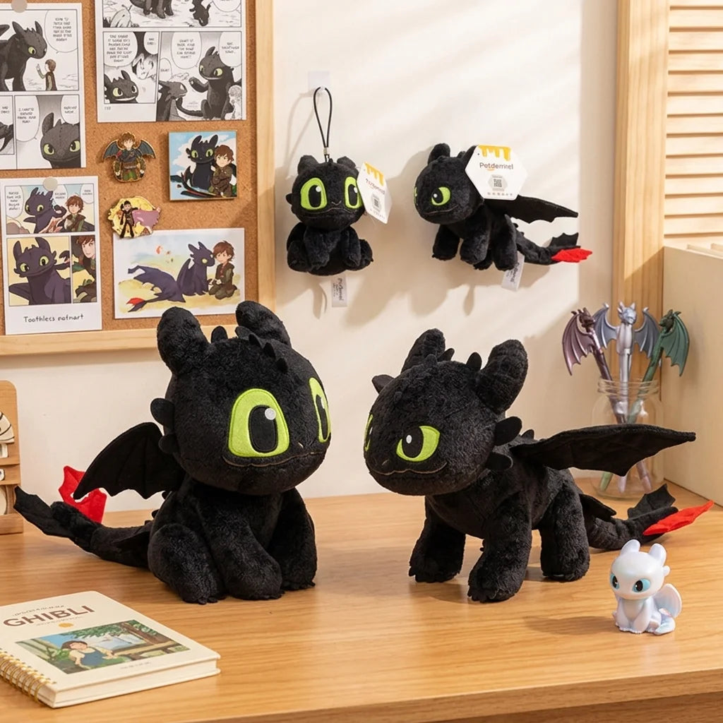 A black soft plush dragon toy resembling a Night Fury, displayed next to various framed artwork and other plush toys.
