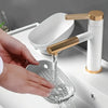 A hand is pouring water into a glass dish from a modern bathroom faucet with a drain tray.