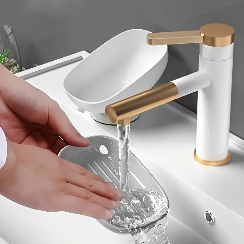A hand is pouring water into a glass dish from a modern bathroom faucet with a drain tray.