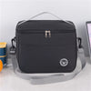 Black thermal insulated lunch bag with an adjustable shoulder strap resting on a white surface.