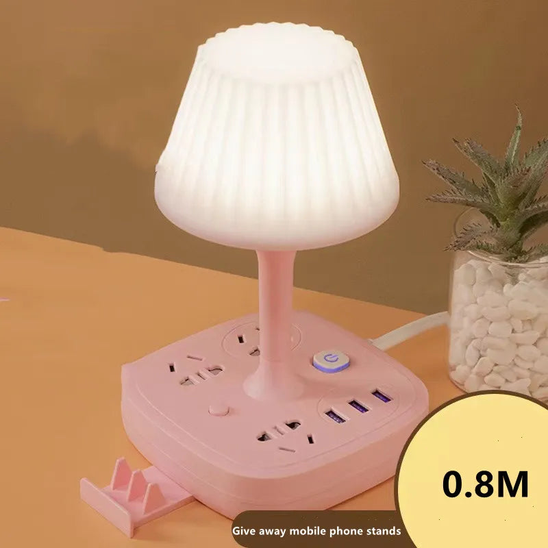 A pink multifunctional desk lamp with a light shade, USB charging hub, and phone holder, shown on a wooden surface.