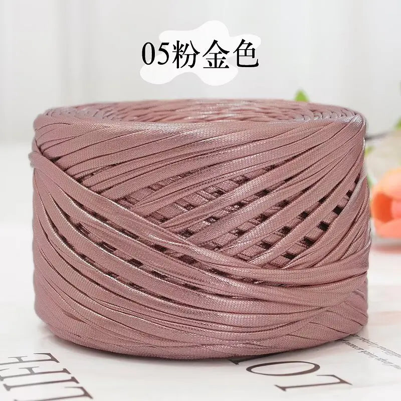 A spool of metallic rose gold flat ribbon yarn for crochet and knitting