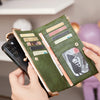 A hand holds a green leather wallet with multiple cards and a phone, resting on a light shelf.