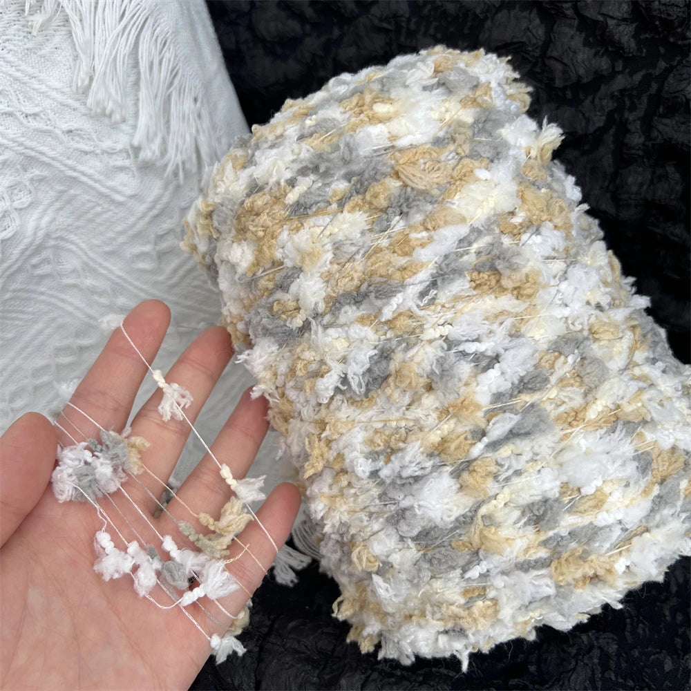 A ball of hand-dyed variegated cotton blend yarn showing gray, white, and gold fibers.