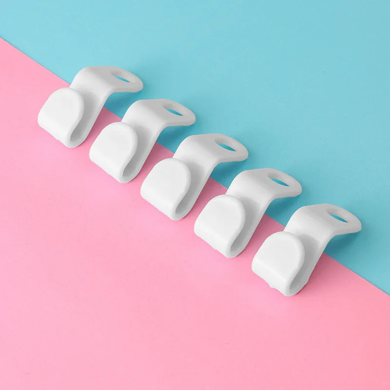 A row of white space-saving cascading hanger connector hooks arranged diagonally on a pink and blue background.