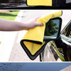 A yellow microfiber cleaning towel is shown being used to wipe a car's exterior surface.