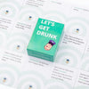 A green box of Let's Get Drunk drinking cards with a cartoon face illustration.