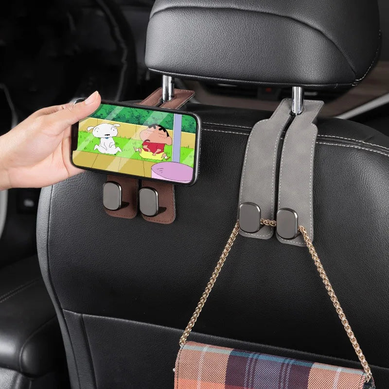 A hand holds a smartphone with cartoon characters, demonstrating a universal car seat back storage hook.