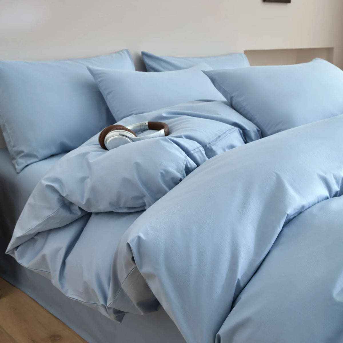 Light blue quilted duvet cover set with matching pillows on a bed.