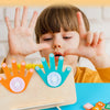 A child demonstrates counting skills using wooden fingers and number blocks on a table.