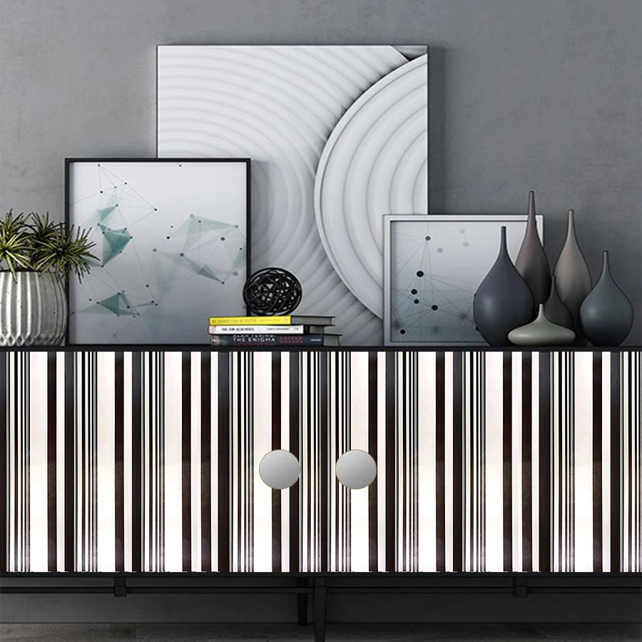 A display of black and white striped self-adhesive wallpaper rolls against a gray wall with abstract artwork.