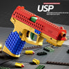 A red and gold building block toy pistol with a blue grip and shell ejecting action is shown on a dark surface.