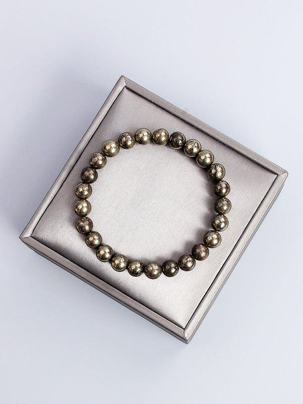 Pulsera hecha de pequeñas piedras naturales de pirita redonda, exhibida en una caja de plata cuadrada.