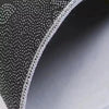 Close-up view of a black geometric non-slip absorbent rug fabric with white stitching.