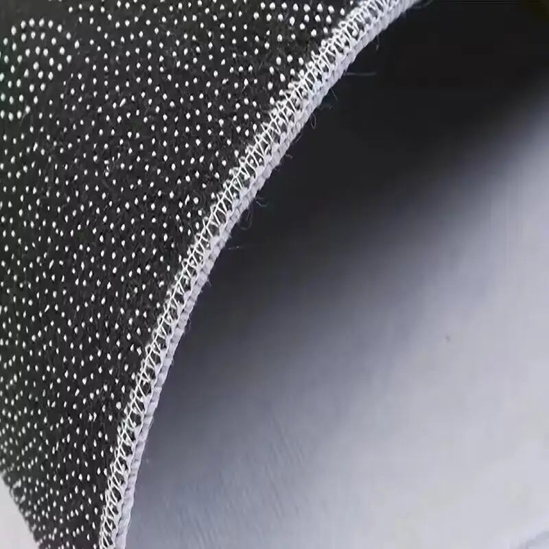 Close-up view of a black geometric non-slip absorbent rug fabric with white stitching.
