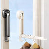A white foldable wall-mounted clothes drying rack with an adhesive mount hanging clothes in a window frame.