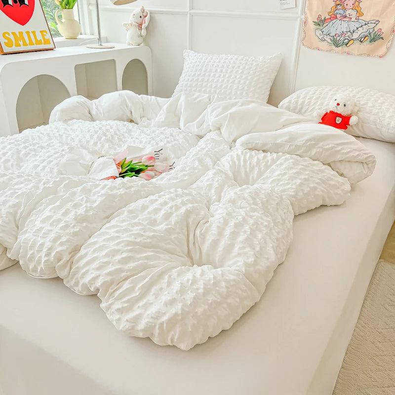 A white lightweight seersucker duvet cover set displayed on a bed with decorative pillows and a stuffed animal.