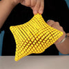 A hand holds a bright yellow 3D printed articulated starfish fidget toy with a textured surface.