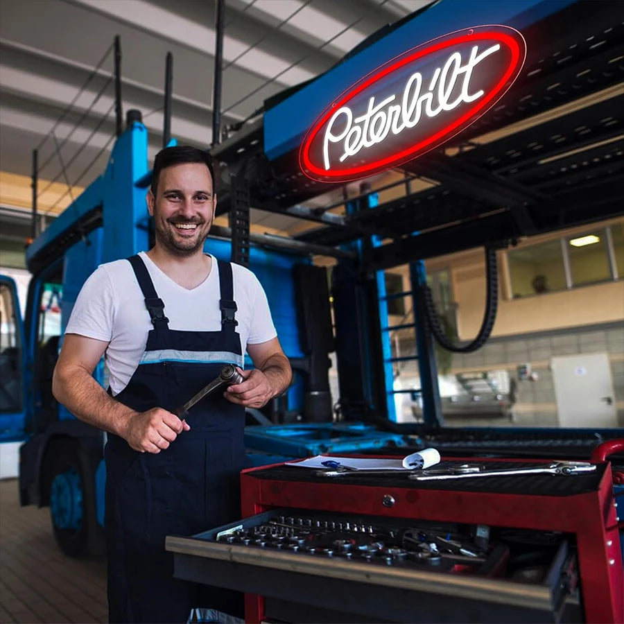 A man stands in front of a red Peterbilt truck neon sign with USB power.
