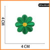 A green embroidered patch shaped like a flower with a yellow center, measuring 4 cm by 4 cm.