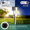A silver solar powered garden lantern light with a translucent yellow glow is shown in an outdoor setting.