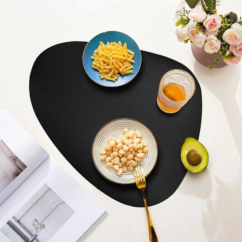 A black placemat features a blue bowl of yellow couscous, a glass of orange liquid, and an avocado slice.