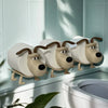A playful animal toilet paper holder resembling a dog is displayed on a bathroom shelf.