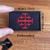 A black embroidered tactical patch featuring a red cross design on a wooden surface.