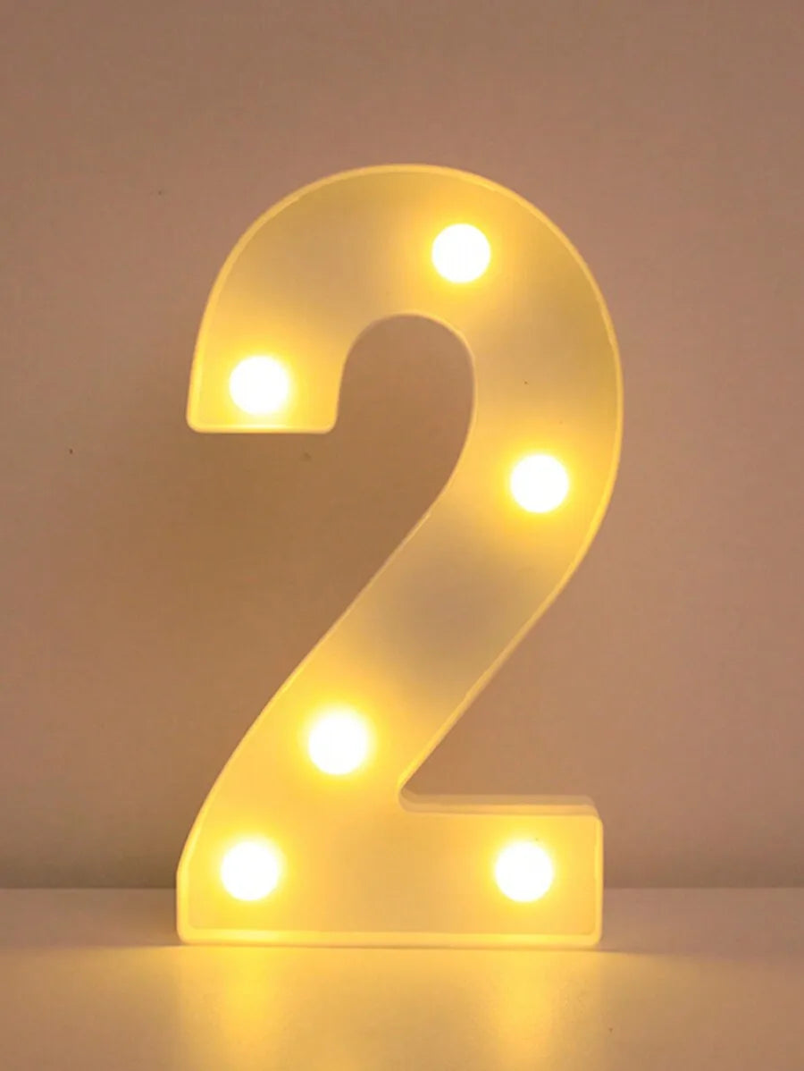 A glowing yellow LED letter night light shaped like the number 2, illuminating the surface below.