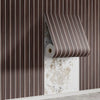 A close-up of wood grain peel-and-stick wall tiles in brown and white stripes mounted on a textured white wall.