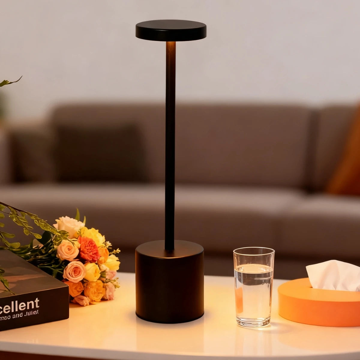 A black rechargeable LED desk lamp with a cylindrical base and a round top, sitting on a white surface.