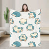 A woman holds up a white blanket featuring cute blue and yellow Snorlax characters.