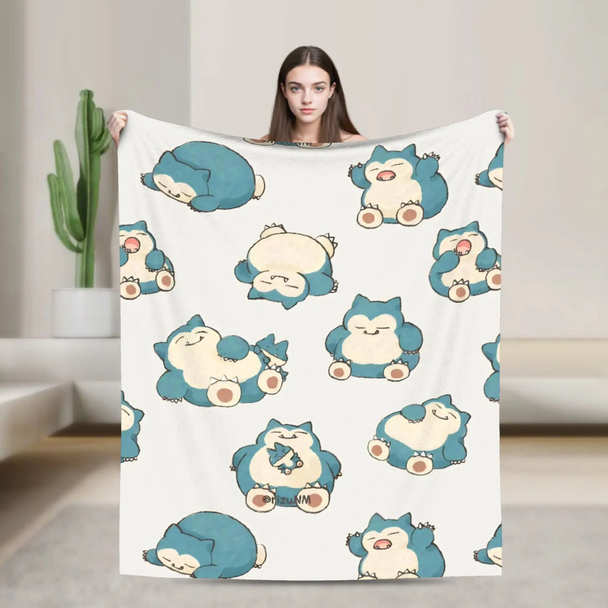 A woman holds up a white blanket featuring cute blue and yellow Snorlax characters.