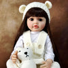 A lifelike silicone baby doll with long dark hair wearing a white knitted headband and vest.