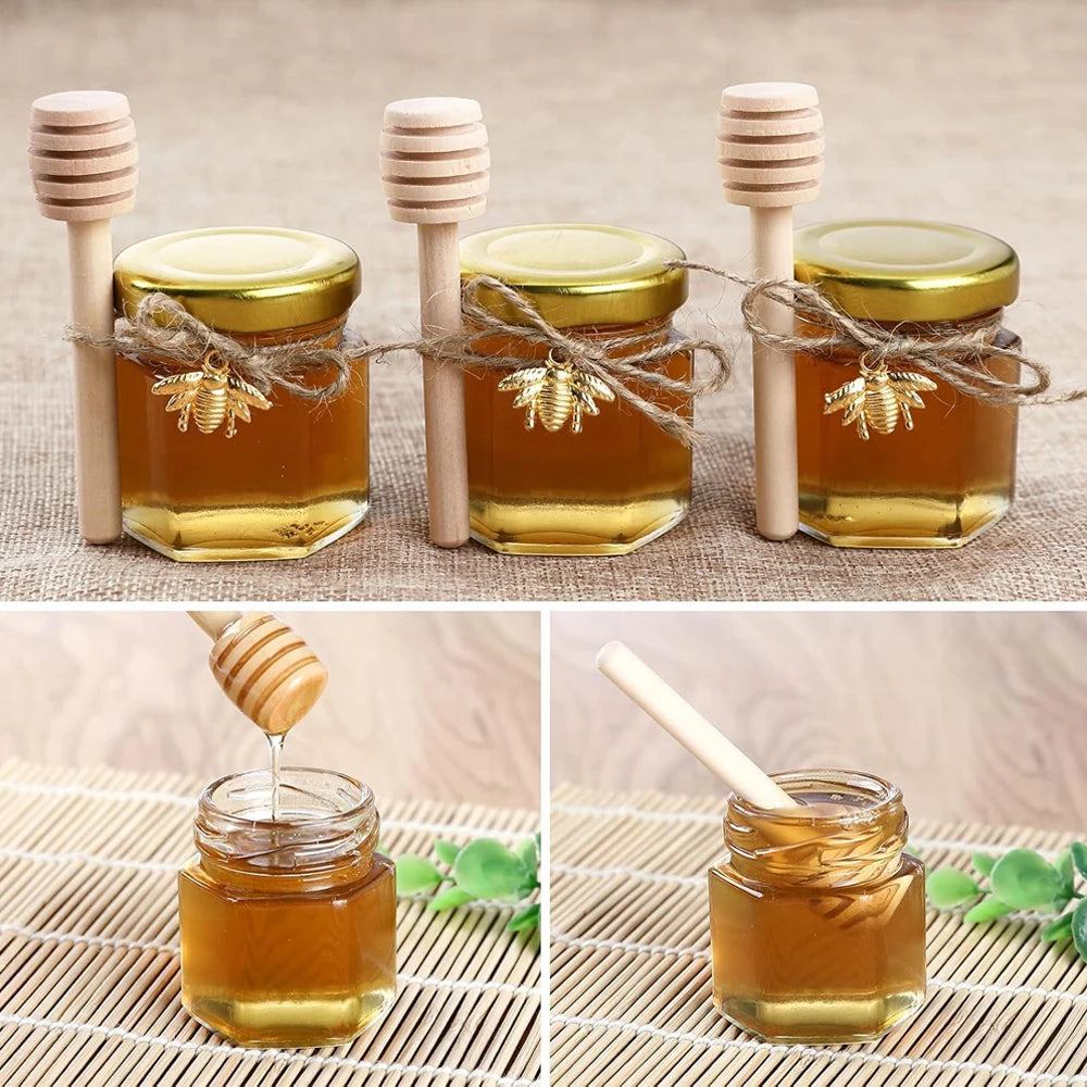 Three glass jars of golden honey with wooden dippers and gold lids arranged on a textured surface.